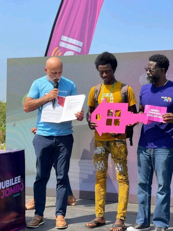 Africell Chief Executive Officer Shadi Gerjawi presenting house documents and keys to winner, Amidu Kamara (in the middle) of Jubilee Jumbo promotion