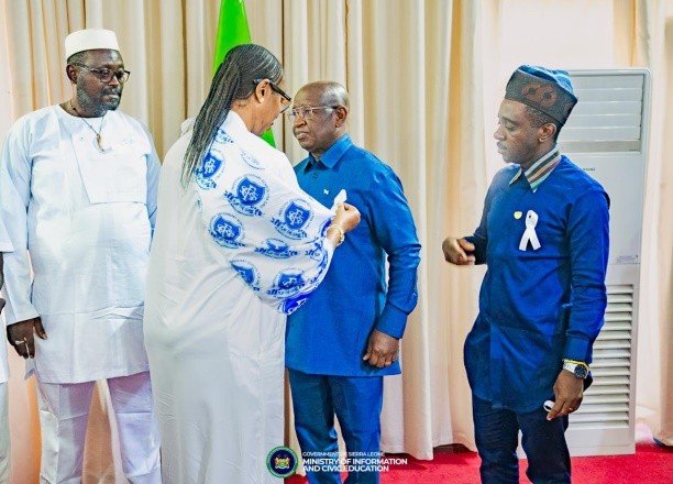 Peace Commission Executive Secretary Pins White Ribbon on President Bio