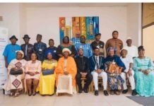 Orange Foundation, UBA and Partners Support National Drive to Tackle English Language Crisis Group of about 18 people posing for a formal group photo indoors, seated in front row and standing behind, with a colorful abstract painting on the wall and a banner to the left; some wear traditional attire and others in suits or dresses.