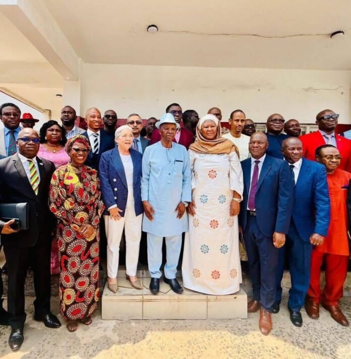 Group of diverse officials and dignitaries in formal attire posing on steps outside a building for a group photo.