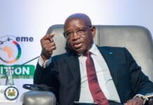 President Bio Unveils “Prevention Before Intervention” Doctrine at Dakar International Forum on Peace and Security in Africa Man in a dark suit and red tie speaks at a conference panel, gesturing with his hand with a logo backdrop behind him.