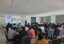 NMA, IGF Launch Four-Day Environmental Management Training for Newly Recruited Geologists, Engineers & Stakeholders Conference room workshop: presenter at the front addressing a large audience seated around tables with a projector screen overhead.
