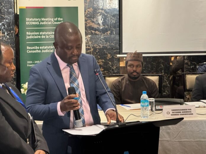 Panel of officials at a formal meeting, with a banner behind them reading ECOWAS, the man in a blue suit speaking into a microphone beside others.