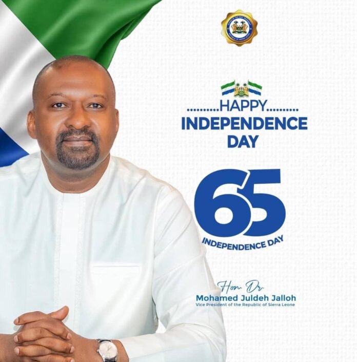 Portrait of Mohamed Juldeh Jalloh, Vice President of Sierra Leone, in white attire with 'Happy Independence Day' and '65' graphics against a flag backdrop.
