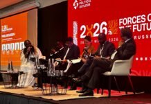AFJN Chief Urges Global Leaders to Integrate Faith into Africa’s Development Agenda at Brussels Summit Panel discussion on stage with five speakers seated in white chairs against a red backdrop reading 2026 Forces of the Future Russia poster
