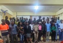 Elba Foundation Backs Fire Safety Bill to Strengthen National Emergency Response Group photo of a diverse crowd in uniforms and casual attire posing in a hall with a banner in the background.