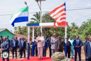 Formal flag-raising ceremony with government officials and security personnel on a red carpet.