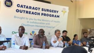 Panel of speakers seated at a long table during a Cataract Surgery Outreach Program event, with a banner behind them.