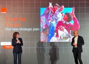Two speakers on a stage presenting a slide that reads 'Trust the Future' and 'Our new strategic plan' beside a vibrant image of young people with a skateboard.