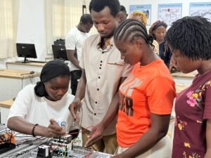 Student-led electronics workshop: a person wires a breadboard while others observe at a lab bench in a classroom setting