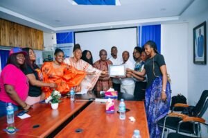 Group of professionals in a conference room presenting a certificate to a recipient, with a framed award in the center on the table behind them.