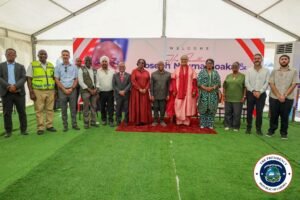 Group of diverse officials and guests posing for a formal portrait inside a tent, on a red carpet with a welcome banner behind them and a Liberia presidency seal visible in the corner of the image.