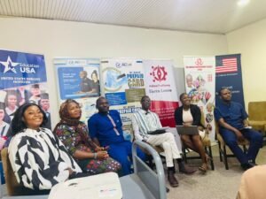 Panel of six adults seated in a row, smiling, with EducationUSA and RC Bank banners in a conference room behind them.” floor settings