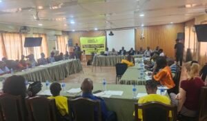 Conference room with attendees seated around long tables, Amnesty International banner at the front.
