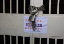 NRA and Yada Williams Draw Daggers Over Rental Tax Claims, Legality of Office Sealing Questioned Lock across a metal gate with a heavy chain and padlock; a posted sign reading 'CLOSED' and 'KEEP OFF' behind the bars.