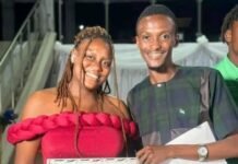 Central University Concludes Students’ Week with Academic Excellence and Social Awards Night Woman in a red off-shoulder dress holds a framed certificate, standing beside a smiling man holding an envelope at a ceremony.