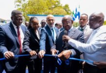 President Bio Officially Launches Partnership with Africell to Relaunch Sierratel as MVNO Officials in suits cut a blue ribbon at an outdoor ceremony, with onlookers and flags in the background.
