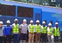 SLRDRRA Conducts Assessment Visit to Kingho Railway and Port in Pepel Group of railway workers in safety vests and hard hats standing on tracks in front of a blue locomotive.