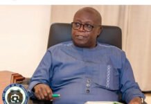Turay Family Demands Speedy Proceedings in Rowal Village Land Conflict Official-looking man in a blue traditional shirt sits in a black leather chair, holding a green pen and notebook; Office of the President seal appears bottom-left.