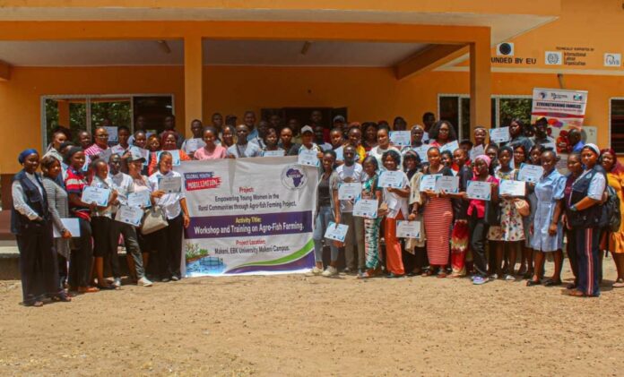 Large group of people outdoors holding certificates and a banner advertising a workshop on agro-fish farming at Makeni EBK University Makeni Campus.
