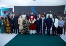 Vice President Joins Leadership Colloquium 2.0, Celebrates President Bio’s Vision and Service Group of diverse dignitaries and attendees posing on stage at a formal event, with a central figure in red traditional attire flanked by officials in suits and dresses.