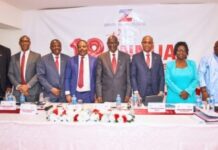 Zenith Bank (SL) Celebrates Profit Surge and Strategic Success at 18th AGM Eight professionals in business attire stand behind a long conference table during a formal meeting, with a branded banner in the background.