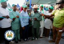 President Julius Maada Bio Inaugurates Kono SLPP Office, Calls for Unity and Loyalty Group of officials and community members participate in a ribbon-cutting ceremony under a tent, marking a public event.
