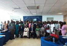 NaMEA Concludes Two-Day Validation Workshop on 10 Government Project Monitoring Reports Group photo of men and women in a conference room, banner reads 'Now is the time for Sierra Leone' in the background.