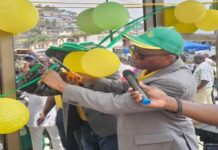 NP (SL) Limited Commissions Modernized Kissy Bye Pass Fuel Station to Enhance Service Delivery Man in a green hat cuts a yellow ribbon at a ceremony while others watch, balloons overhead and a microphone held nearby.