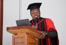 Njala University Hosts Nigerian Monarch as Academic–Traditional Partnership Deepens Graduating speaker in red and black gown delivers a speech at a wooden lectern, holding a microphone and tablet.