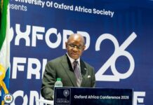 President Bio Challenges African Leaders to Anchor Stability and Drive Reform Man in a dark suit and glasses speaks at a lectern, with a blue backdrop reading 'Oxford Africa Conference 2026'.