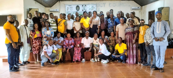 Large group of men and women posing for a group photo in a hall with Ministry of Agriculture banners in the background.