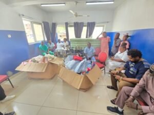 People in a small room with large boxes of folded clothes, likely a clothing donation center awaiting sorting or distribution.