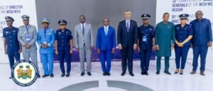 Group of ten officials in military uniforms and suits posing for a formal conference photo, with a government seal on the left and banners in the background.