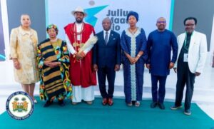 | The Calabash Newspaper Seven people in formal and traditional attire pose on a stage, with a screen behind reading Julius Maada Bio.