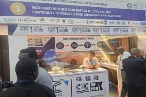 | The Calabash Newspaper Exhibition booth at a trade show with staff seated at a desk and large banners about integrated export services in English and Chinese, with visitors nearby.
