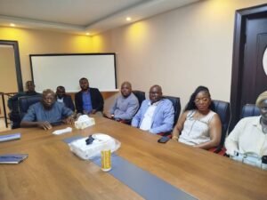 Eight professionals seated around a large conference table in a meeting room, facing the camera.