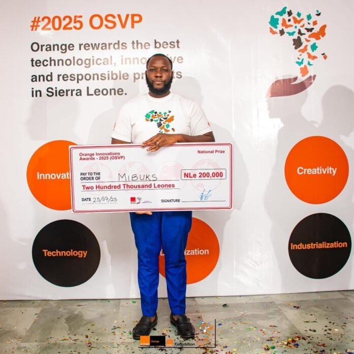 OSVP 2025 Winner Edward Kamara Man holding an oversized cheque for Two Hundred Thousand Leones at a #2025 OSVP event; backdrop shows orange circles with Innovation, Creativity, Technology, and Industrialization labels.