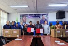 Chinese Medical Team Hands Over Critical Anti-Viral Supplies to Ministry of Health Diverse group standing behind a conference table, holding red folders, with boxes on the table and a banner that reads '300 Days of Activism for Sierra Leone' in the background.
