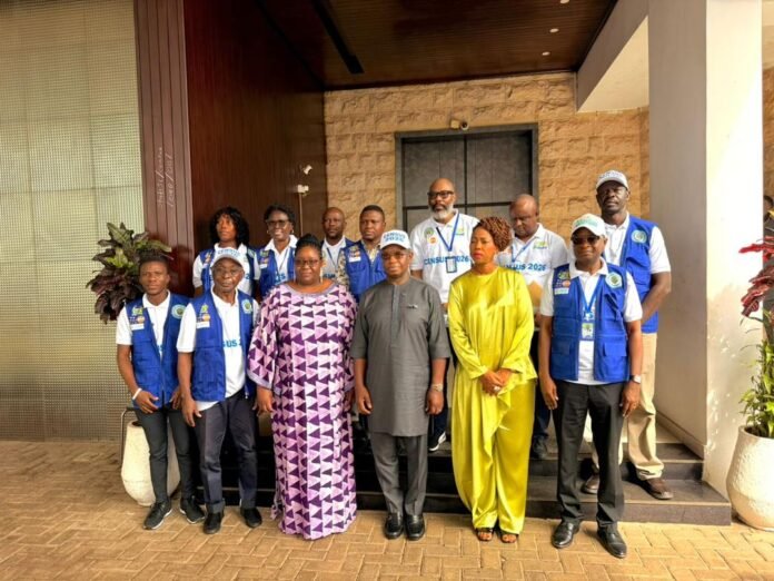 Group of men and women wearing blue census 2026 vests posing on steps outside a building.