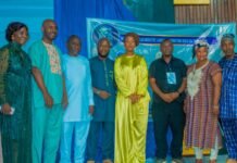 First Lady Launches SL Film Guild Strategic Development Plan 2026–2030 Nine people in colorful traditional outfits posing for a group photo at an event, with a blue banner behind them.