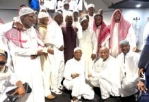 Vice President Dr. Mohamed Juldeh Jalloh Calls for Peace and Unity at Hajj 2026 Celebration in London Group of Muslim men in white traditional attire posing for an indoor group photo, with several kneeling in front and others standing behind.