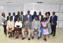 Audit Service Sierra Leone and SLEITI Sign MoU to Strengthen Extractive Sector Transparency A diverse group of adults in business attire pose for a formal group photo indoors, in a bright office with partition walls behind them.
