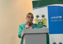 UNICEF Backs Innovative Education Financing as Sierra Leone Pursues Sustainable Reforms Woman in a teal blazer speaks at a podium with a UNICEF backdrop behind her.