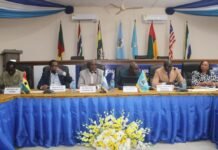 RMU Chairman Calls for Urgent Reforms to Strengthen Maritime Education Six officials seated at a long panel table in a conference room, with microphones and nameplates, flags behind them and a blue tablecloth with a yellow floral arrangement in front.