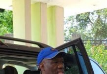 Moyamba Delegates Declare Overwhelming Support for Musa Tarawally’s 2028 Flagbearer Bid Man in a light blue shirt and blue cap steps out of a dark SUV with the door open, holding a phone.
