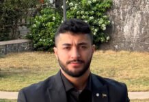 VIP Trading Clears Long-Standing Police Rice Backlog, Delivers Six Bags to Every SLP Officer Portrait of a man with short dark hair and a beard, wearing a black suit, standing outdoors near a stone wall and greenery.