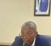 Lands Minister Pursues Mortgage Financing and Student Housing Support at ‘Shelter Afrique’ AGM in Morocco Man in a blue suit speaks into a handheld microphone at a desk with papers in front.