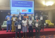 Finance Ministry Reaffirms Commitment to Transparency at 2025 Open Budget Survey Launch Group of people on a stage holding certificates, posing for a photo during a budget presentation event, with a slide showing '2025 OPEN BUDGET' in the background.