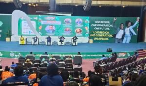 | The Calabash Newspaper Panel discussion on a large stage with five speakers seated in white chairs; banner reads 'One Region. One Generation. One Future.'